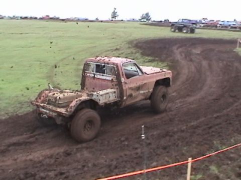 1994 Ford Explorer - A red pickup truck navigates a muddy course during an event.