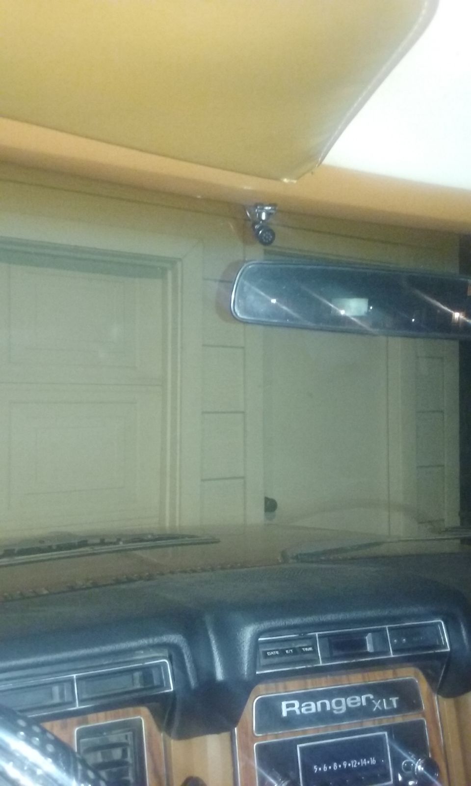 Truck interior with Ranger XLT dash badge, rearview mirror, and view through windshield into a garage