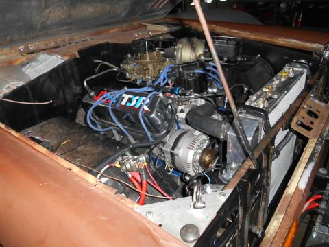 1972 Ford Bronco - The engine bay of a classic vehicle, likely a 1972 Ford Bronco, is shown with a V8 engine, carburetor, radiator, and battery visible. The e…