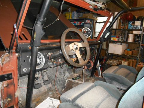 1972 Ford Bronco - Interior view of a modified Ford Bronco, showing a roll cage, aftermarket steering wheel, and racing seats. The dashboard has a prominent t…