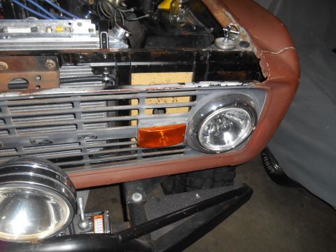 1972 Ford Bronco - Close-up front view of a vintage Ford Bronco's grille and headlight assembly, showing rust and modifications. The vehicle appears to be und…