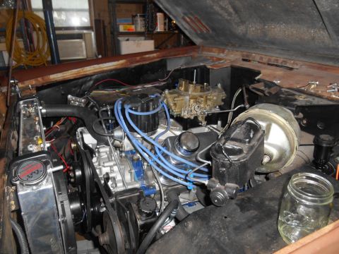 1972 Ford Bronco - The engine bay of a classic vehicle, likely a 1972 Ford Bronco, is shown with the hood open. Visible components include the engine, carbure…