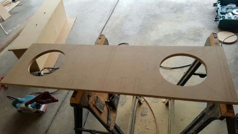 1996 Ford Bronco - A piece of MDF board with two large circular cutouts is laid across sawhorses. A belt sander is visible in the lower left corner.