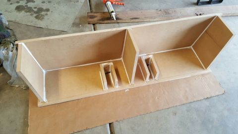 1996 Ford Bronco - A custom-built MDF enclosure with white sealant applied to the seams sits on a piece of cardboard. A caulk gun is visible in the background.