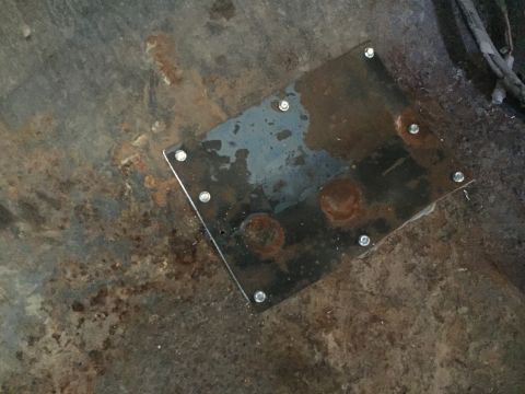 1979 Ford Bronco - A square metal plate with several bolts is attached to a rusty, weathered surface. The plate appears to be a repair or reinforcement piece…