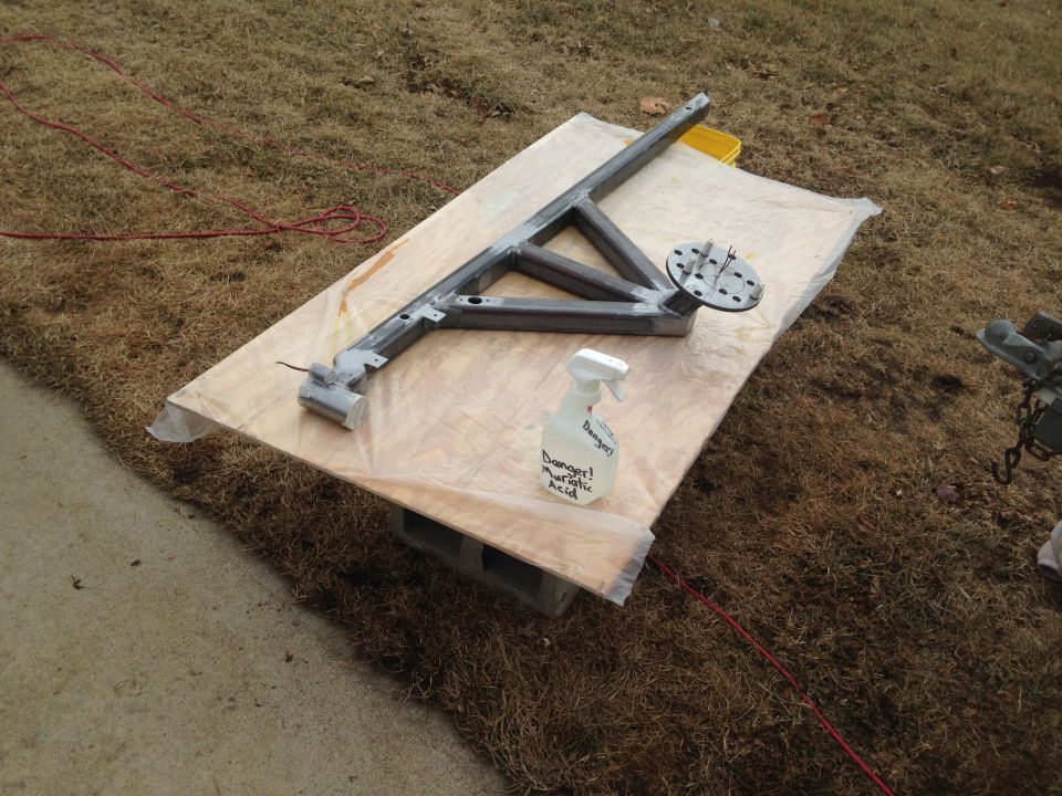 Metal frame structure on a wooden board with a spray bottle.