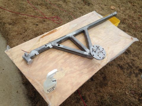 1979 Ford Bronco - A metal frame structure is laid out on a wooden board outdoors. A spray bottle with a warning label is visible in the foreground.