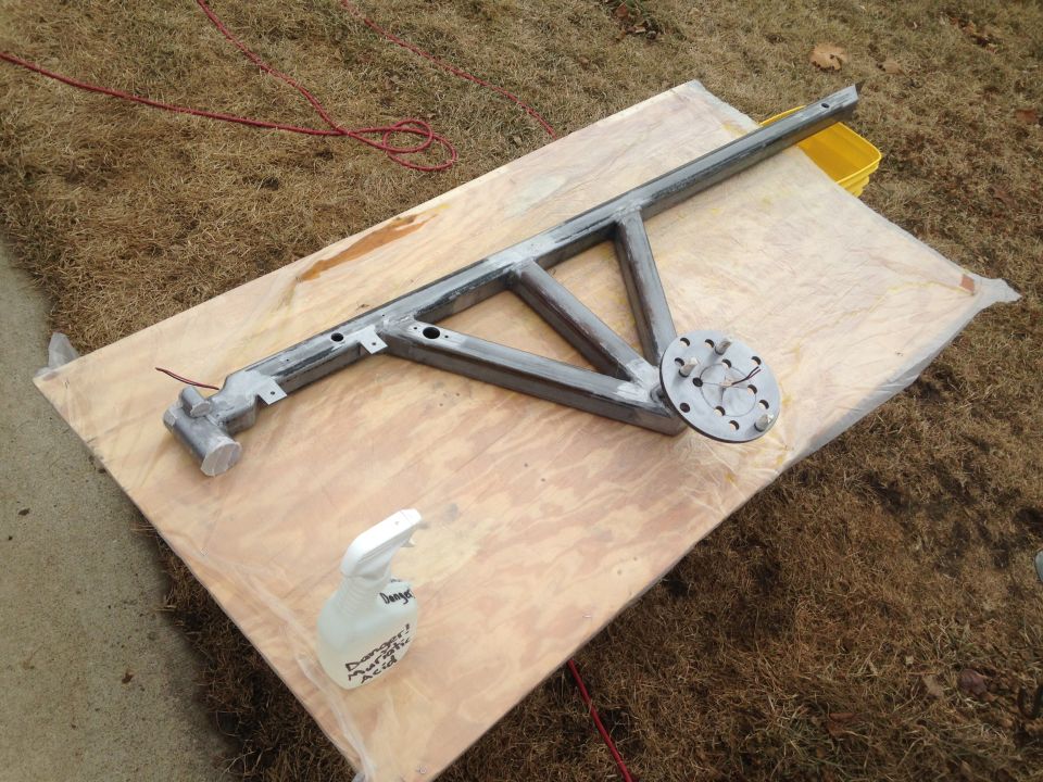 Metal frame structure on a wooden board with a spray bottle.