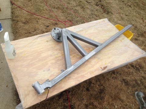 1979 Ford Bronco - A metal frame assembly, possibly a trailer hitch or support structure, is laid out on a wooden board covered with plastic sheeting. A spray…