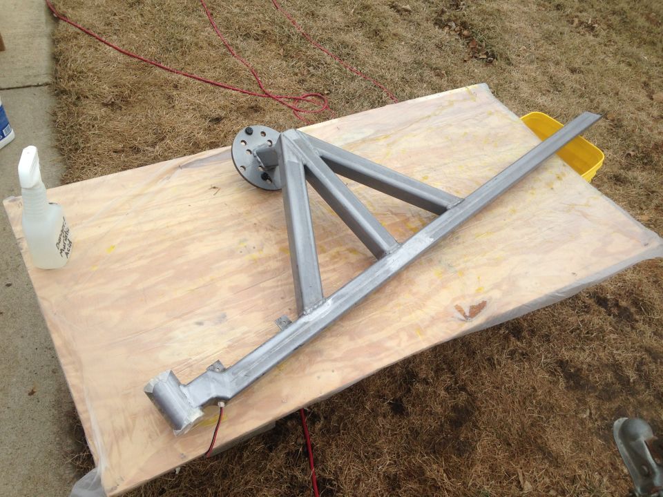 Metal frame assembly on a wooden board with a spray bottle and yellow bucket
