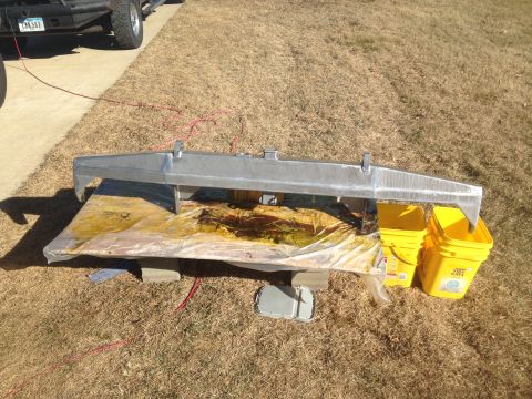 1979 Ford Bronco - A silver metal part, possibly a bumper or frame component, is shown resting on a tarp-covered surface outdoors. Two yellow buckets are plac…