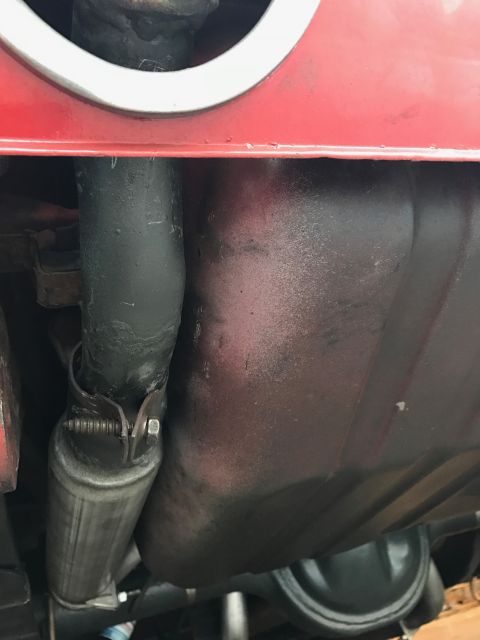 1965 Ford Mustang - Underside view of a vehicle showing a portion of the fuel tank and exhaust system, with a red painted body panel above.