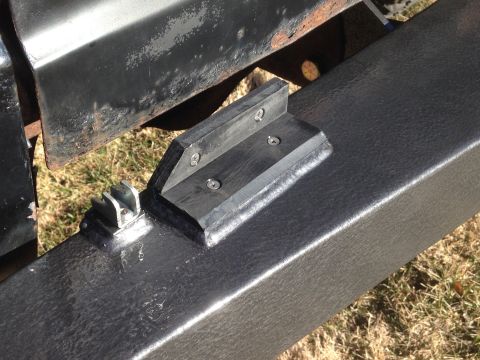 1979 Ford Bronco - A close-up view shows a black textured metal bumper with two black rubber or plastic brackets attached. One bracket has three screws, and t…