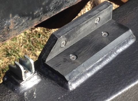 1979 Ford Bronco - A close-up view shows a metal bracket with teeth attached to a black painted surface, next to a black rubber bumper assembly secured with s…
