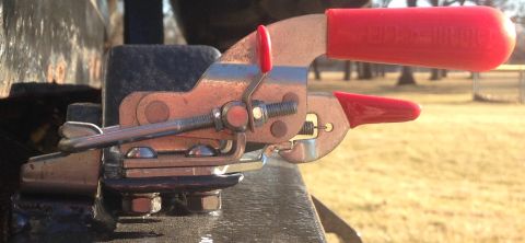1979 Ford Bronco - A close-up shot shows a metal toggle clamp with red handles, attached to a dark-colored surface. The clamp is secured with bolts and nuts,…
