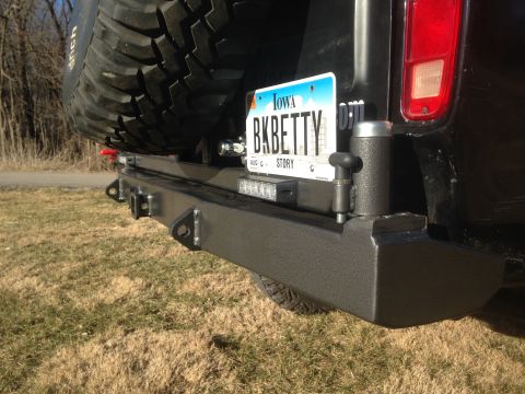 1979 Ford Bronco - The rear of a black SUV, likely a Ford Bronco, is shown with a custom heavy-duty bumper and a spare tire mounted above it. A license plate…