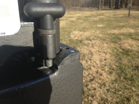 1979 Ford Bronco - A close-up view of a black metal part with a T-shaped handle attached to a textured black surface. The part appears to be a mechanism or le…