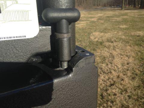 1979 Ford Bronco - A close-up view of a black metal lever mechanism attached to a textured black surface, possibly part of a vehicle's interior or exterior ac…