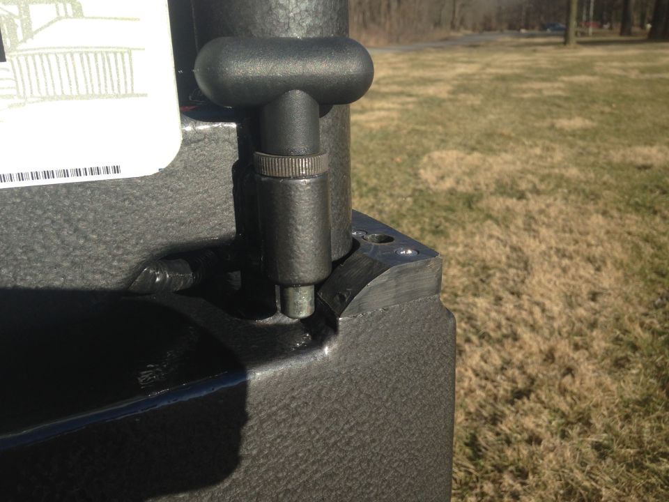 Close-up of a black metal lever with a T-handle on a textured surface.
