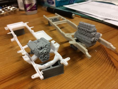 1989 Ford Bronco - Model car components, including chassis and engines, are laid out on a wooden table.