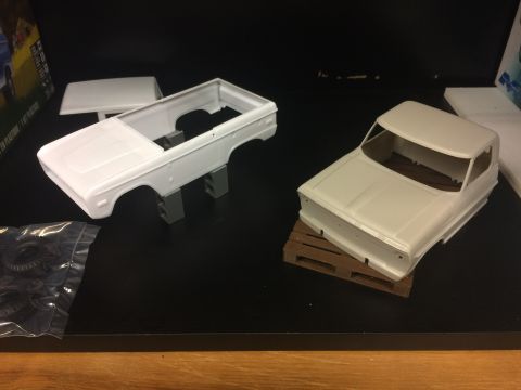 1989 Ford Bronco - Unassembled model car bodies and parts are laid out on a shelf.