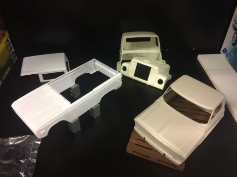 1989 Ford Bronco - Unassembled plastic model truck bodies and components are displayed on a shelf, awaiting assembly.