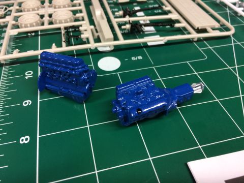 1989 Ford Bronco - Model engine parts are laid out on a cutting mat next to unassembled model kit pieces.