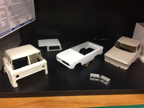 1989 Ford Bronco - Unassembled model car bodies and parts are laid out on a shelf.