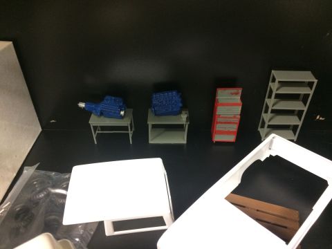 1989 Ford Bronco - Model car parts including an engine and transmission are displayed with a tool chest and shelving unit.