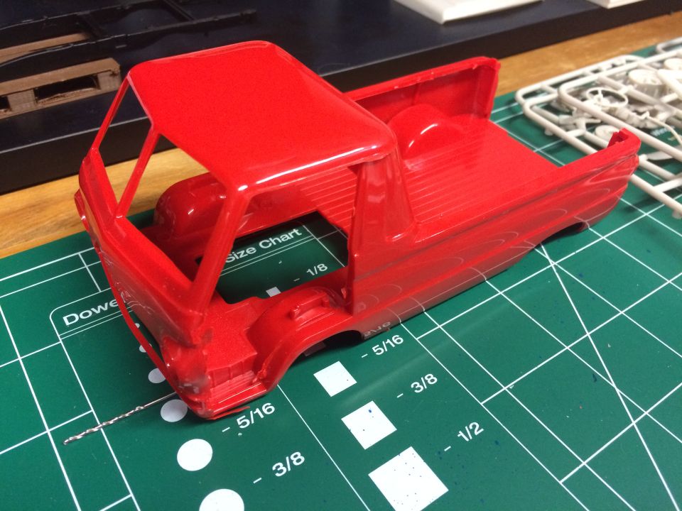 Red plastic model truck body on a green cutting mat with measurement markings