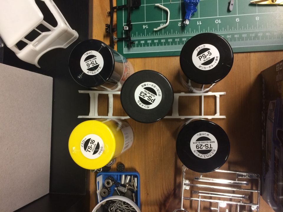 Model car body and spray paint cans including yellow, black, and gun metal