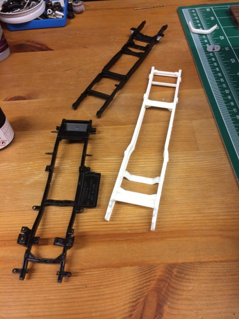 1989 Ford Bronco - Model car chassis frames are laid out on a wooden workbench next to a cutting mat.