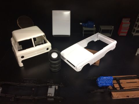 1989 Ford Bronco - Various unassembled model car components are laid out on a dark surface, ready for assembly.
