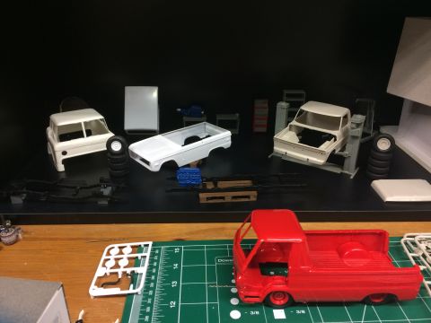 1989 Ford Bronco - Model car parts and unassembled model vehicles are laid out on a shelf and a cutting mat.