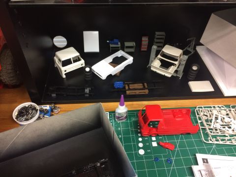 1989 Ford Bronco - Various model car parts and unassembled kits are spread across a workspace, ready for building.