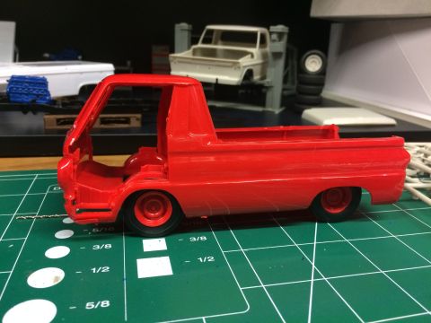 1989 Ford Bronco - A partially assembled red model truck sits on a cutting mat, with other model kits and parts visible in the background.
