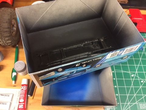 1989 Ford Bronco - A model car kit box is shown with a black chassis inside, and a blue Ford truck graphic on its exterior.