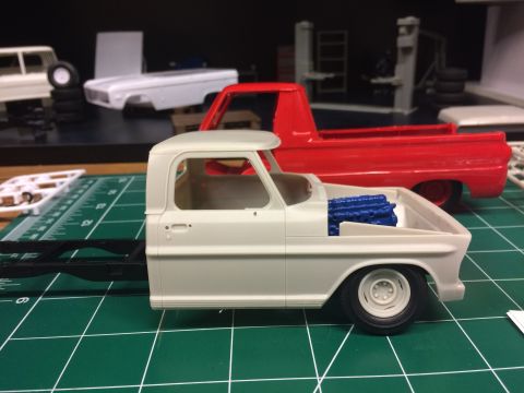 1989 Ford Bronco - Unassembled model truck parts are laid out on a green cutting mat, with a red truck body in the background.