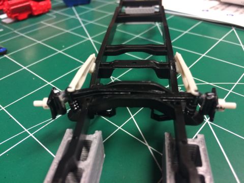 1989 Ford Bronco - A model truck chassis is shown with its suspension components assembled on a green cutting mat.