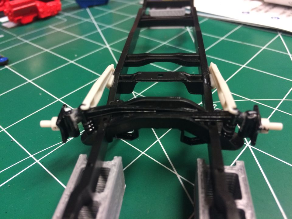Model truck chassis with suspension components on a green cutting mat