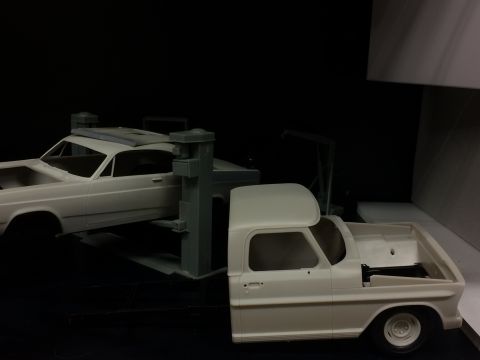 1989 Ford Bronco - Two unfinished model vehicles are displayed against a dark background. In the foreground, a model pickup truck cab is shown, and in the bac…