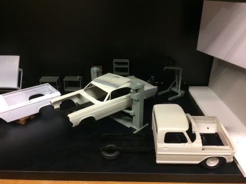 1989 Ford Bronco - A collection of unpainted model car parts are displayed on a black surface with a black background. Visible parts include a truck bed, a ca…