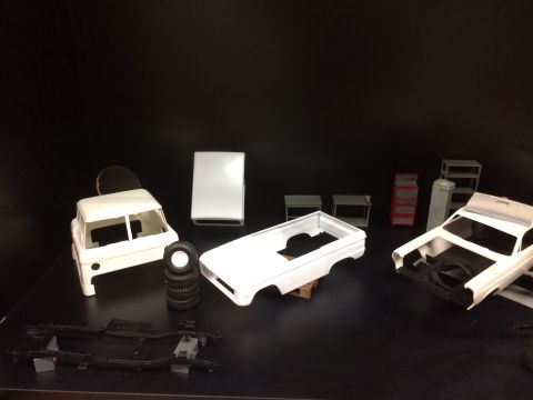 1989 Ford Bronco - Several unassembled plastic model car parts are laid out on a black surface against a black background. Visible parts include a truck cab,…