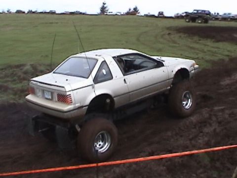 1994 Ford Explorer - A modified Nissan Pulsar NX with oversized tires navigates a muddy off-road course.