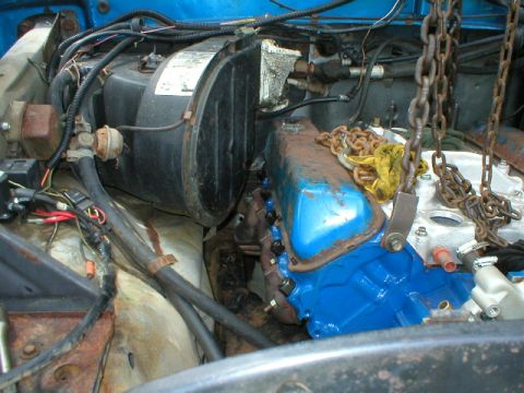 1978 Ford Bronco - Engine bay components are visible, including a blue engine block and rusty exhaust manifold, with chains from an engine hoist.