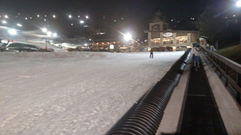 Ski resort base area lit at night with a conveyor lift