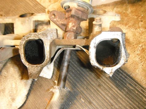 1995 Ford F-150 - A close-up, overhead view of two intake ports on a rusty metal engine component, likely an intake manifold, with visible carbon buildup ins…