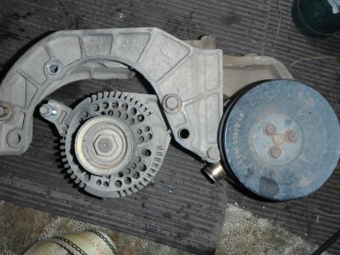1995 Ford F-150 - A close-up view of an alternator and pulley assembly, likely from a 1995 Ford F-150, is shown mounted on a grey bracket. Text on the pulley…