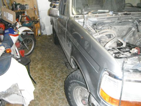 1995 Ford F-150 - A silver Ford F-150 pickup truck is parked in a garage next to a dirt bike. The hood of the truck is open, revealing the engine compartment.