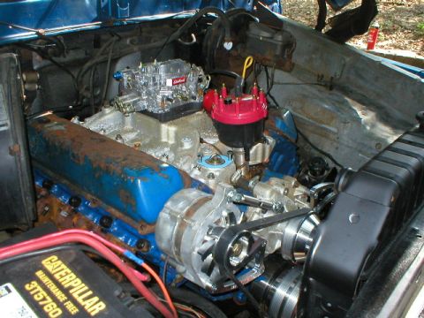1978 Ford Bronco - Close-up of an engine bay a carburetor, distributor, and battery.